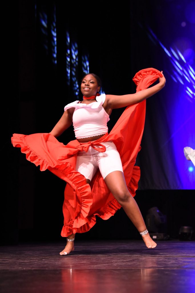 Dancer in a red and white costume performing on stage.